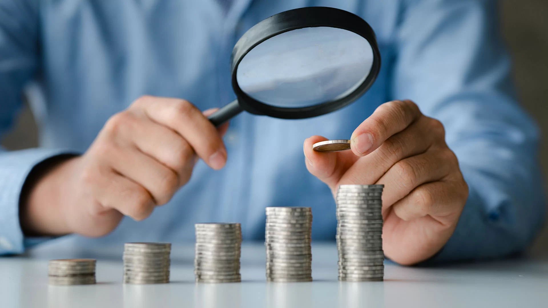 Lupa analisando pilhas de moedas